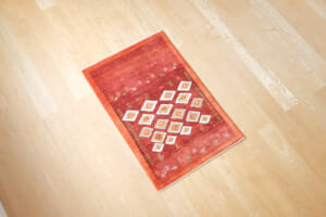 茜色にひし形デザインのギャッベ